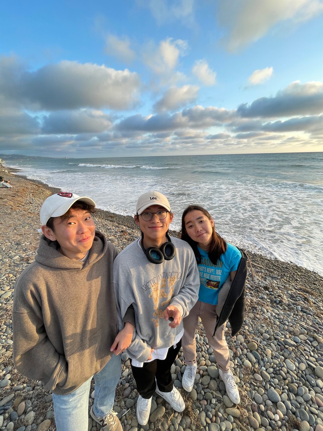 three friends on a pebble beach at sunset